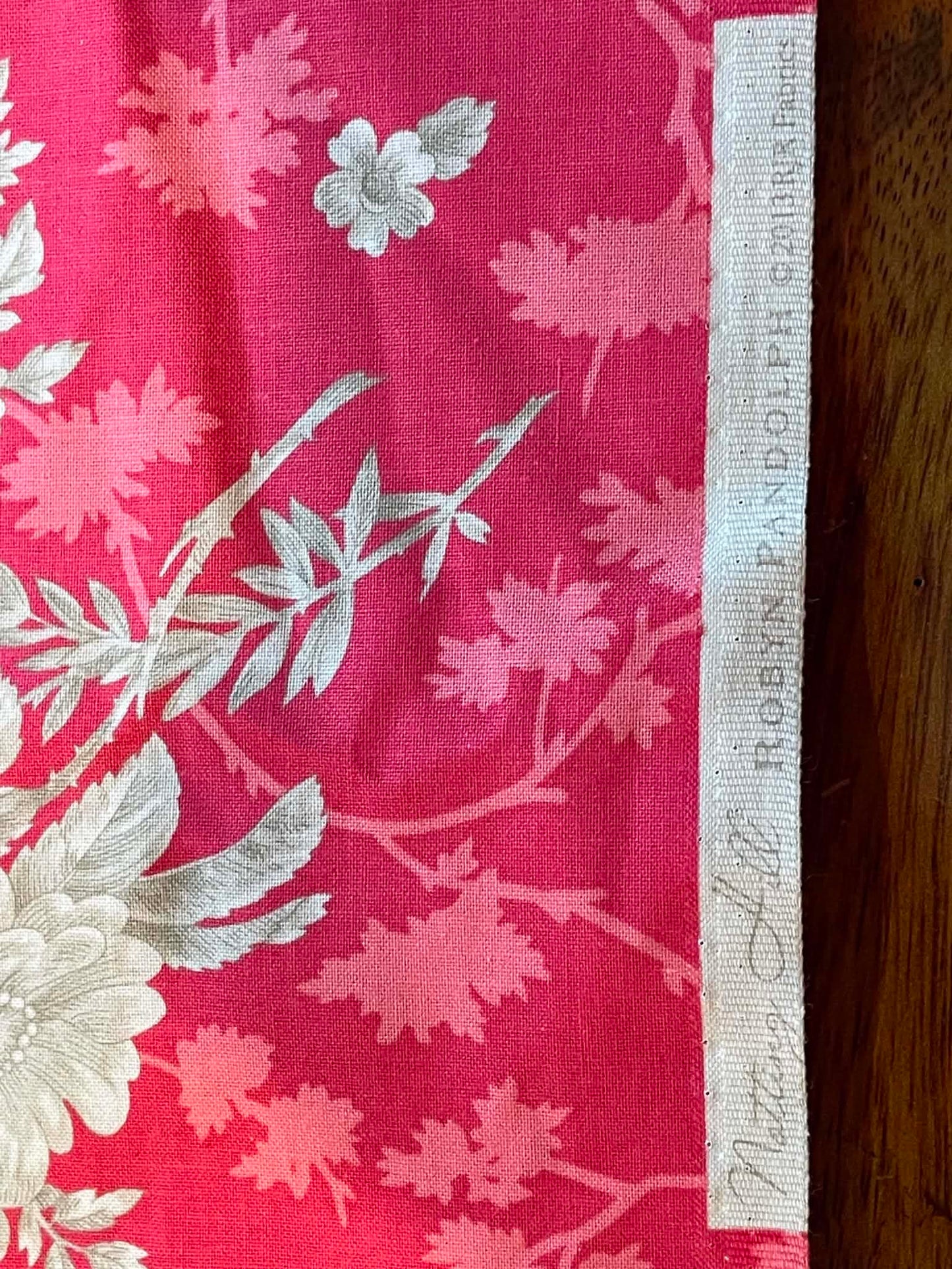 Notting Hill. Tan floral on muted red background. Sold by the yard.
