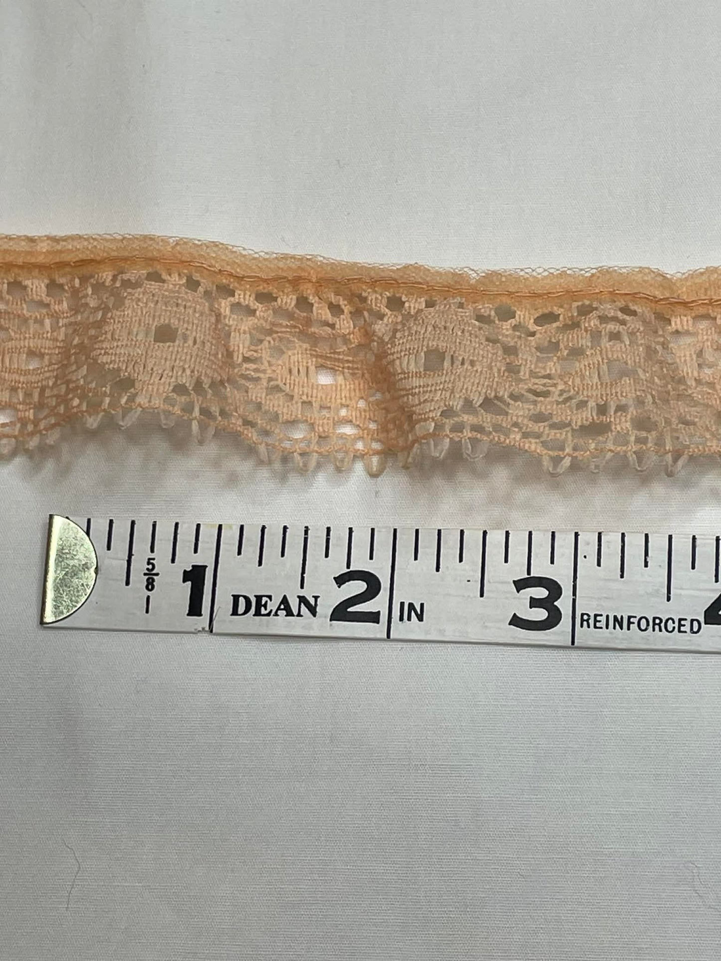 1 1/4" wide peach lace trim. Sold by the half yard.