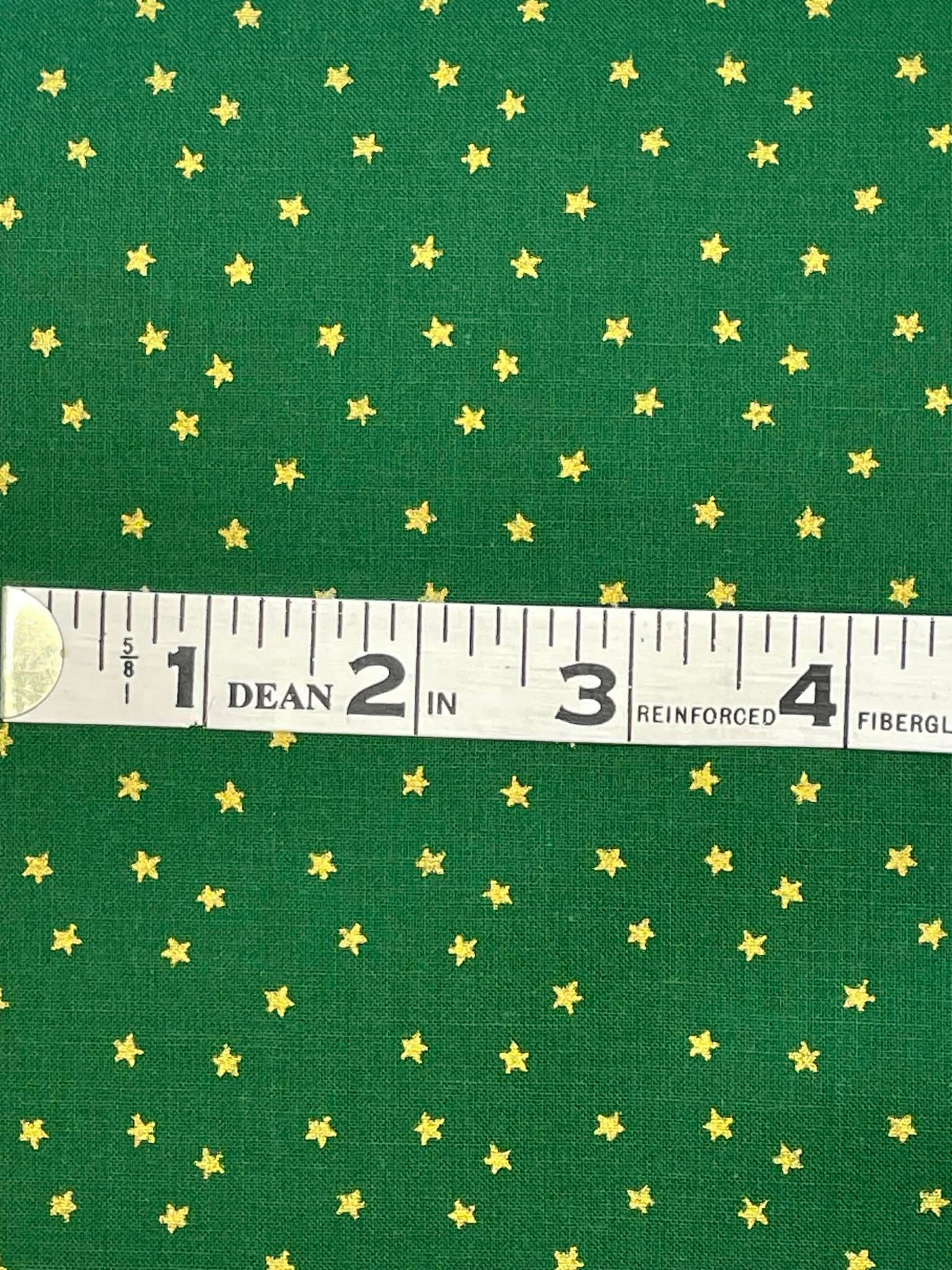 Gold stars on dark green background. Sold by the yard