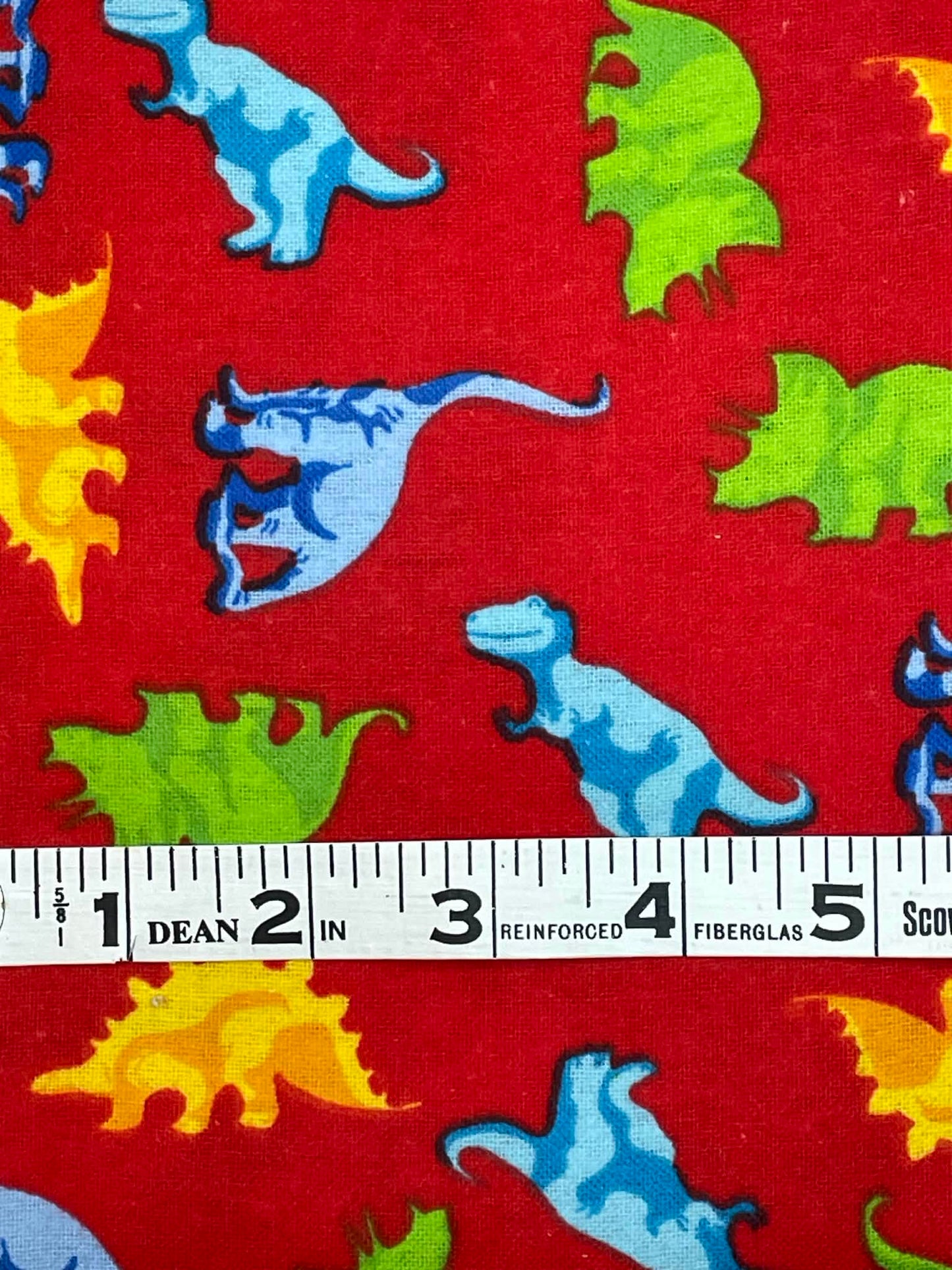 Flannel dinosaurs on red background fabric by the yard.