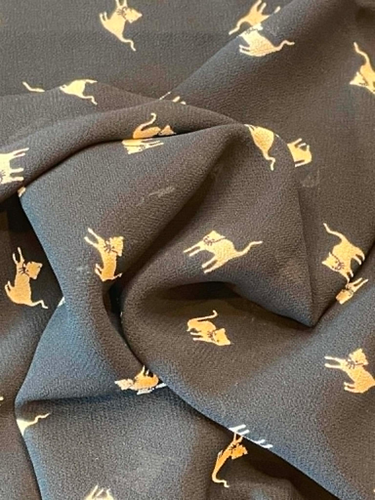 Crepe tan cats on black background.  Sold by the 1/2 yard.