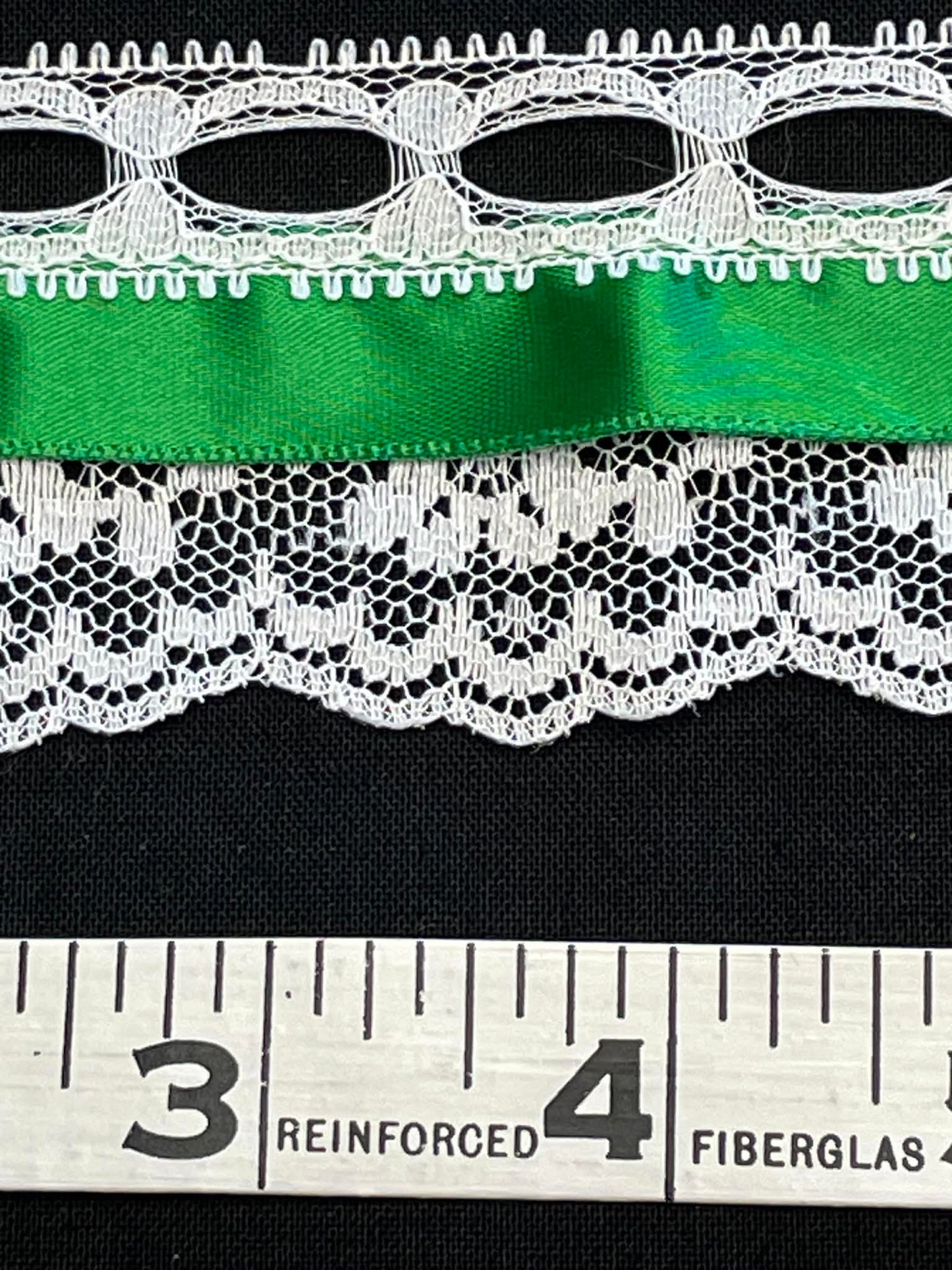 2" wide lace with green satin ribbon.  Sold by the half yard.