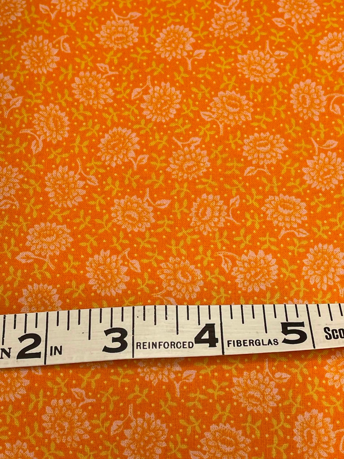 Orange and white flowers on orange background.  Sold by the half yard.