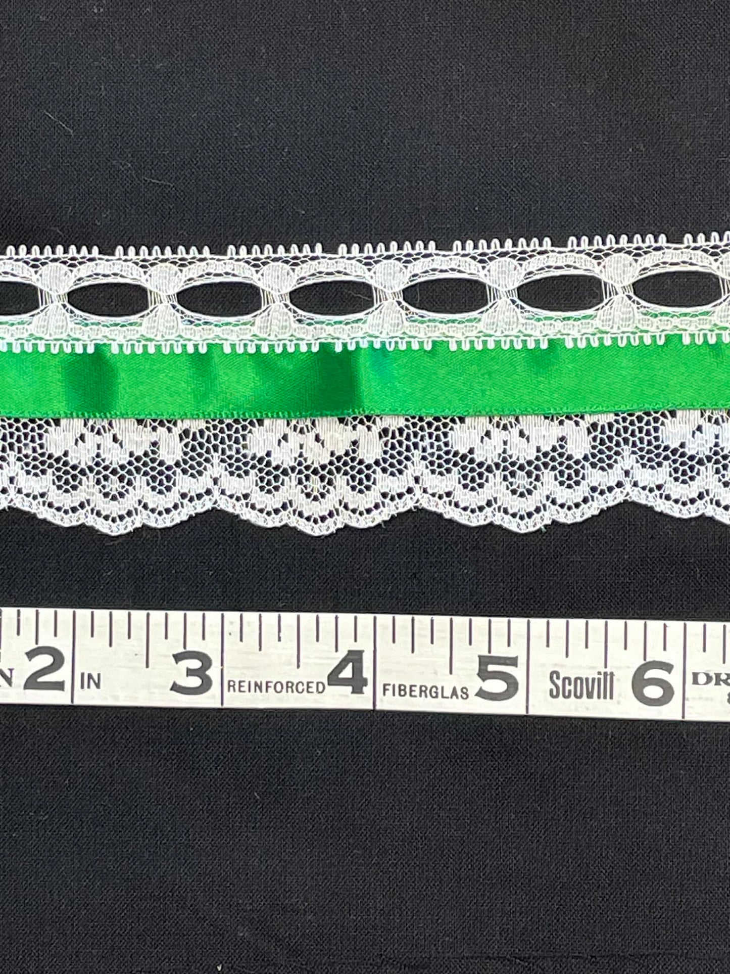 2" wide lace with green satin ribbon.  Sold by the half yard.
