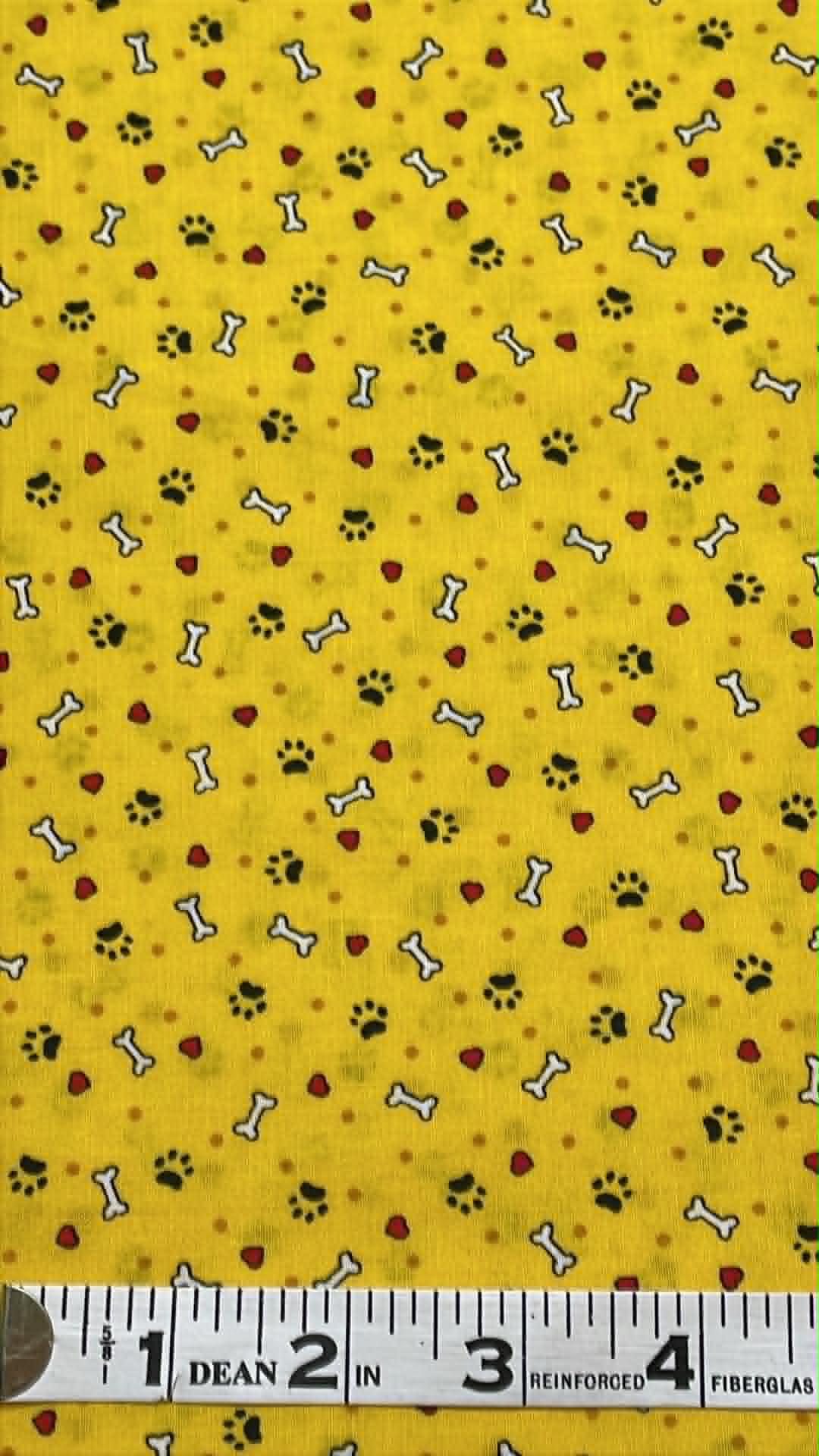 Black paw prints, white bones and red hearts on yellow background.  Sold by the half yard.