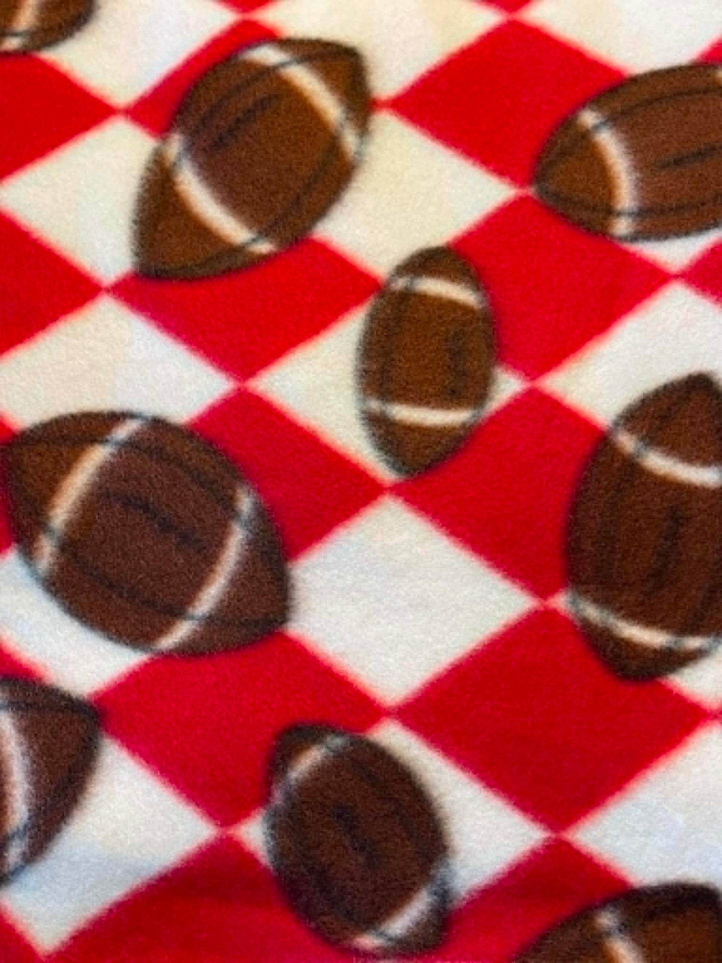 Footballs on red and white check background fleece.  Sold by the half yard.