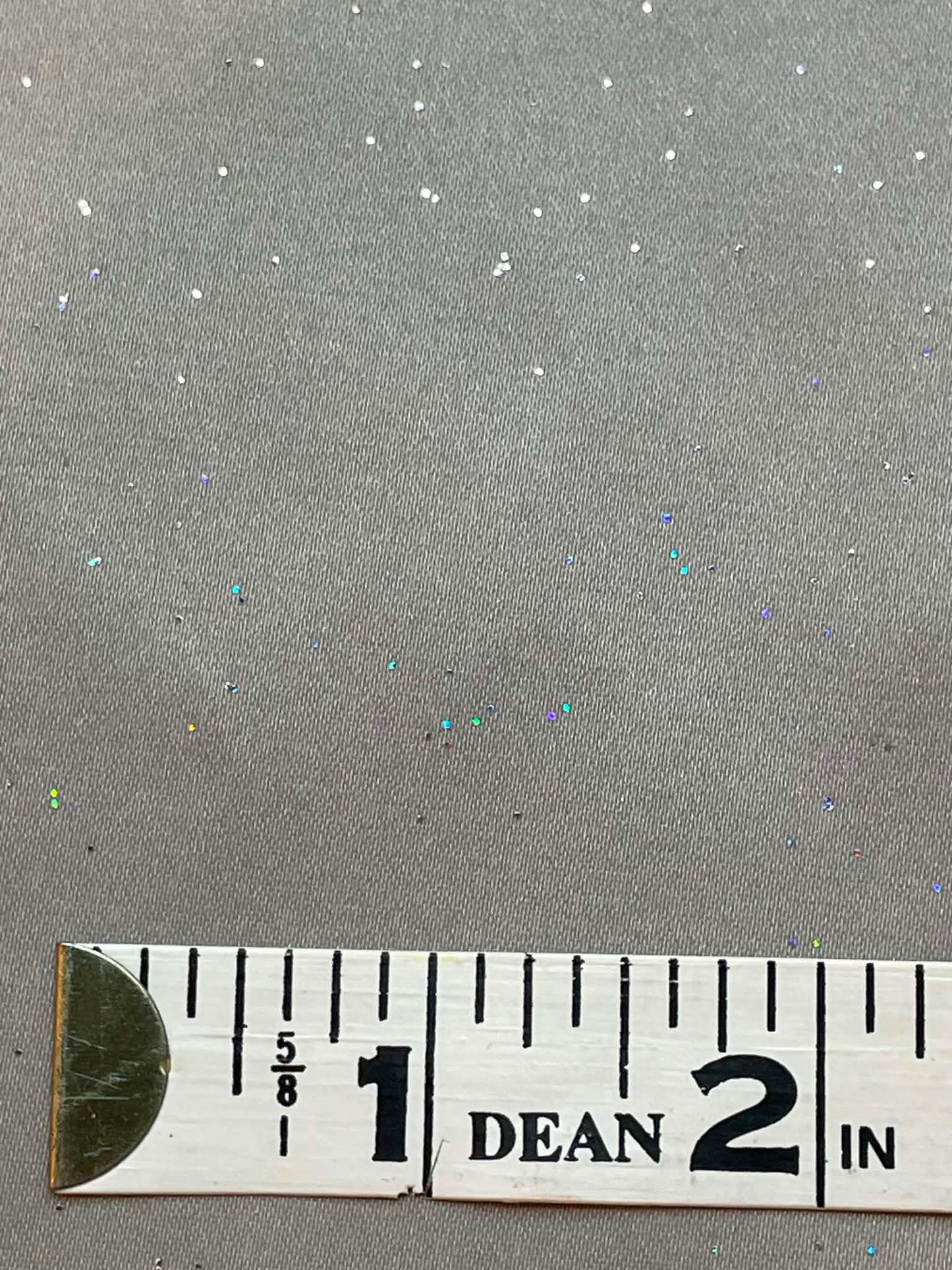 Gray satin with multi-colored sparkles throughout.  Sold by the yard.