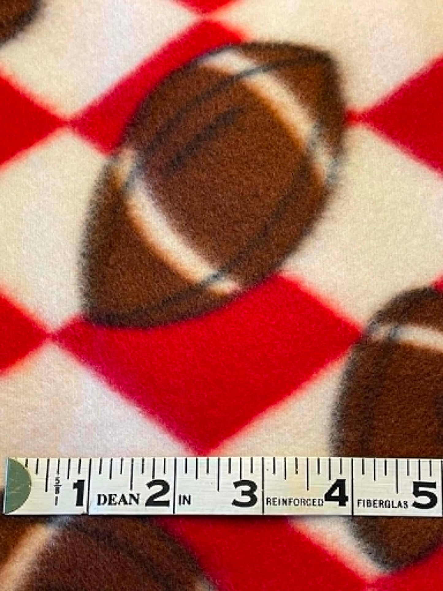Footballs on red and white check background fleece.  Sold by the half yard.